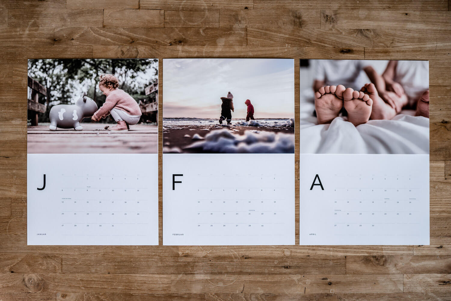Flatlay einzelne Seiten des Fotokalenders 2022 ausgedruckt und mit Fotoabzügen bestückt, Kinderfotos