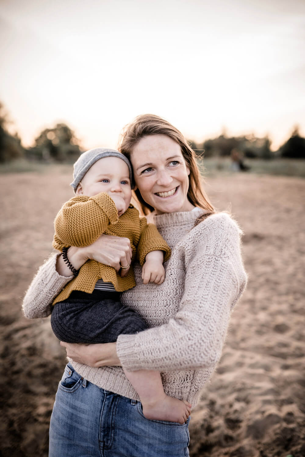 Mutter hat kleinen Sohn auf dem Arm, schauen in die Ferne, lachen, Familienbilder bei Sonnenuntergang am Hufeisensee