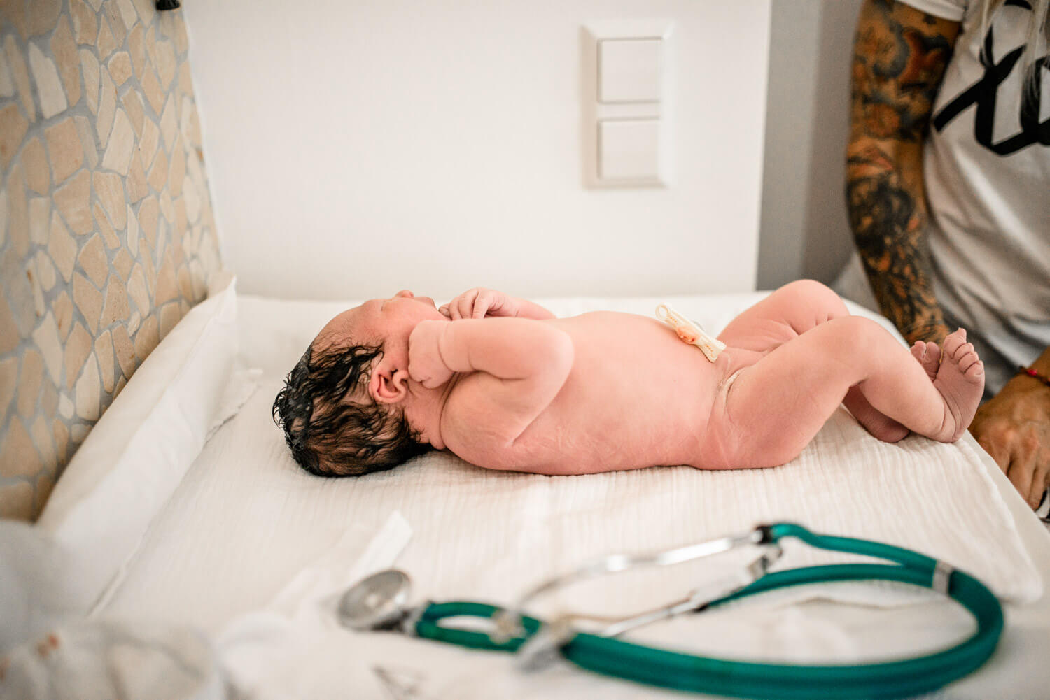 Hebamme untersucht ein gerade geborenes Baby, Baby liegt auf Wickeltisch