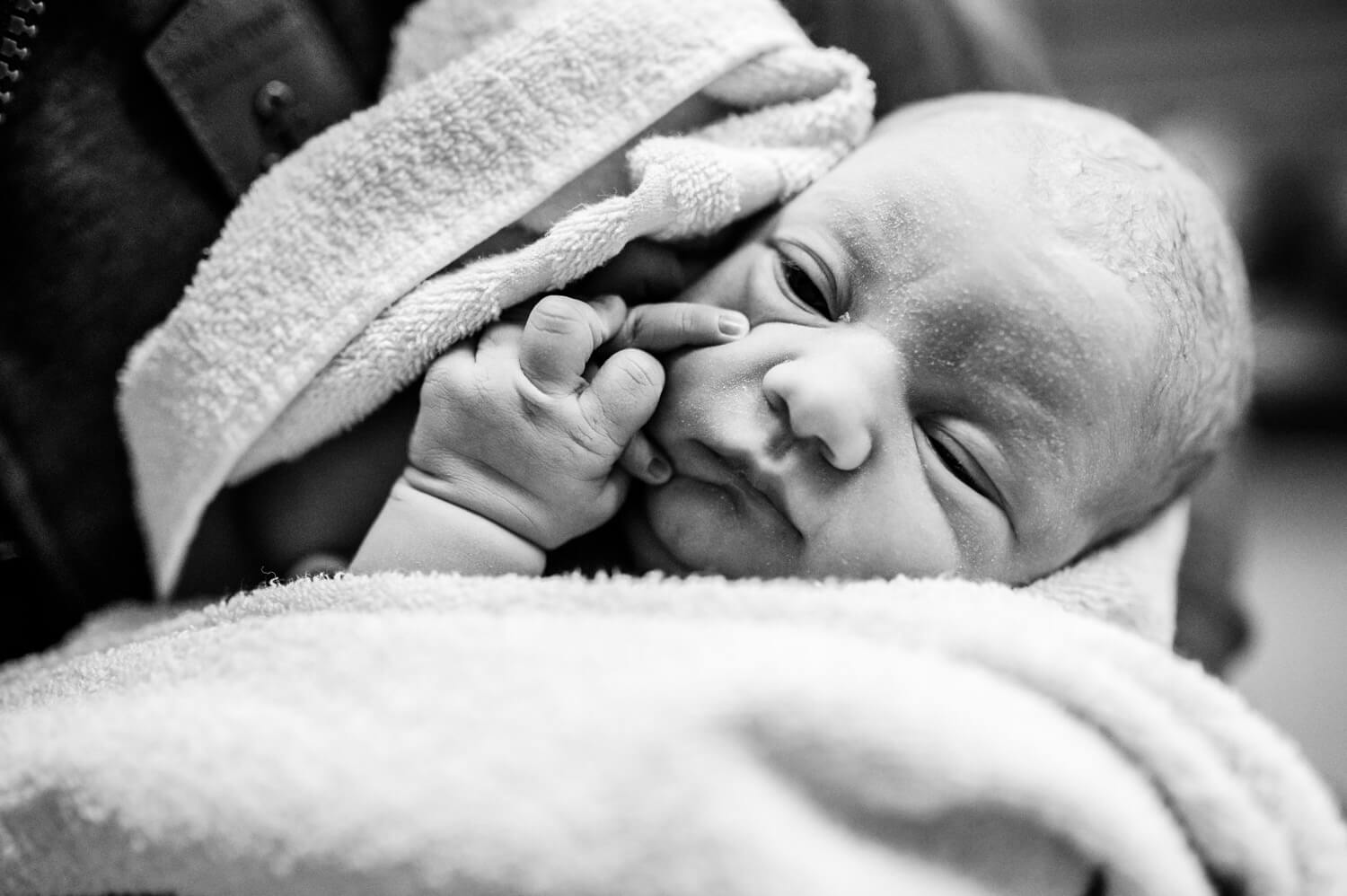 Portrait eines gerade geborenen und in ein Handtuch gewickeltes Baby im Krankenhaus auf Papas Arm