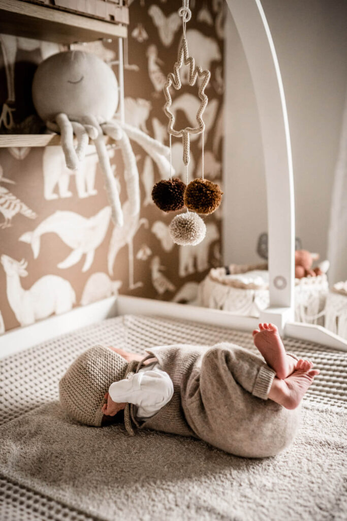 Baby liegt auf Wickeltisch, über ihm hänge Mobile, Babyfotos in Burgwedel