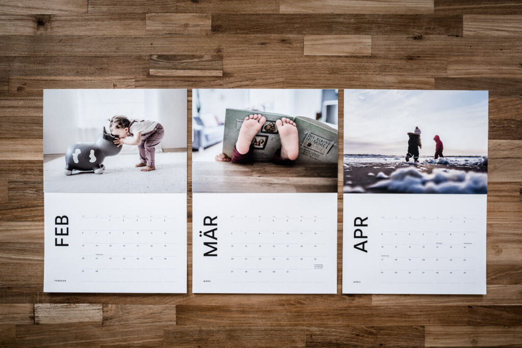 Flatlay einzelne Seiten des Fotokalenders 2023 ausgedruckt und mit Fotoabzügen bestückt, Kinderfotos