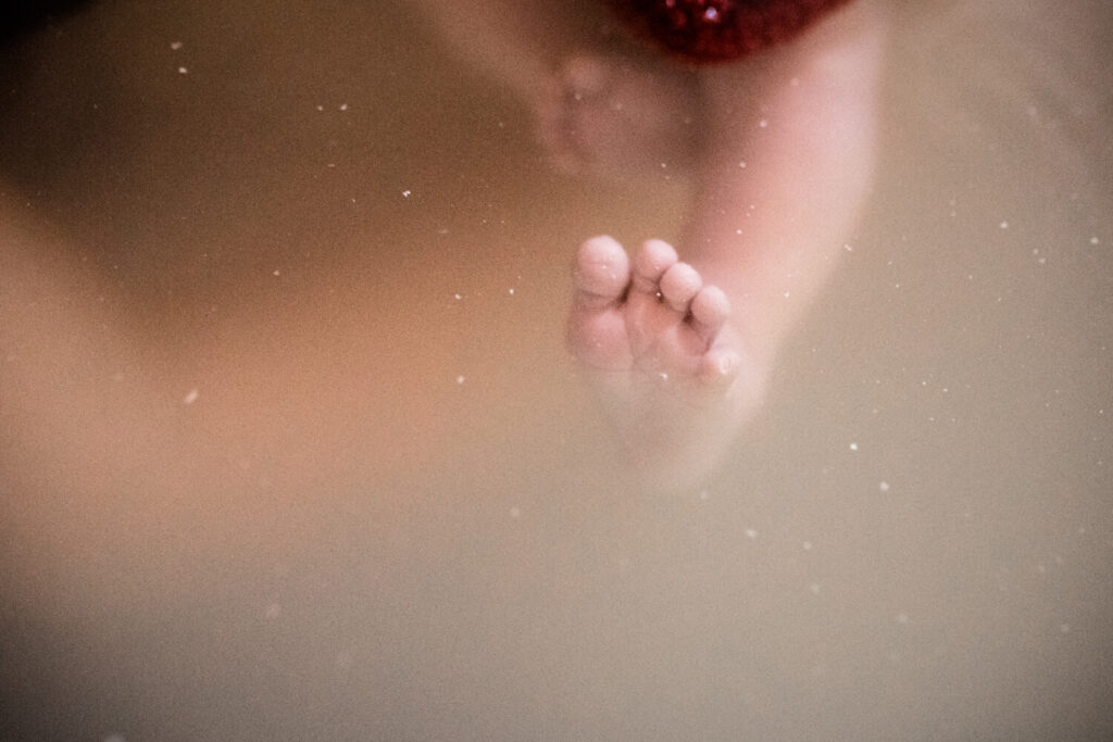 Detailaufnahme eines Fuß eines gerade geborenen Babys im Wasser des Geburtspools, wann geburtsfotografen kontaktieren