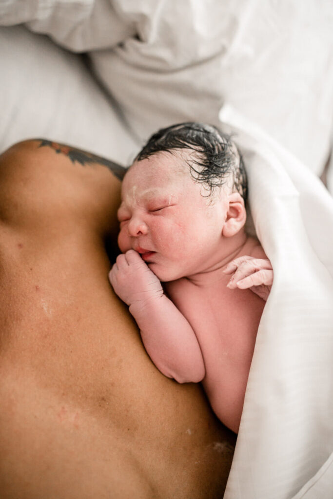 Gerade geborenes Baby liegt bei Papa im Arm, Geburtsreportage in Geburtshaus, was ist geburtsfotografie
